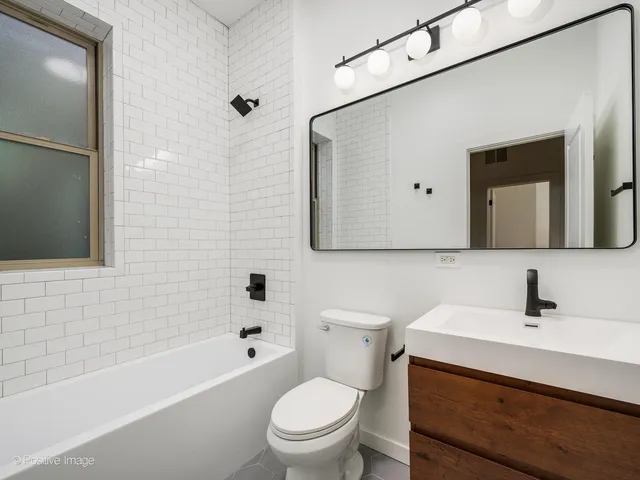 a bathroom with a toilet a sink a mirror and bathtub