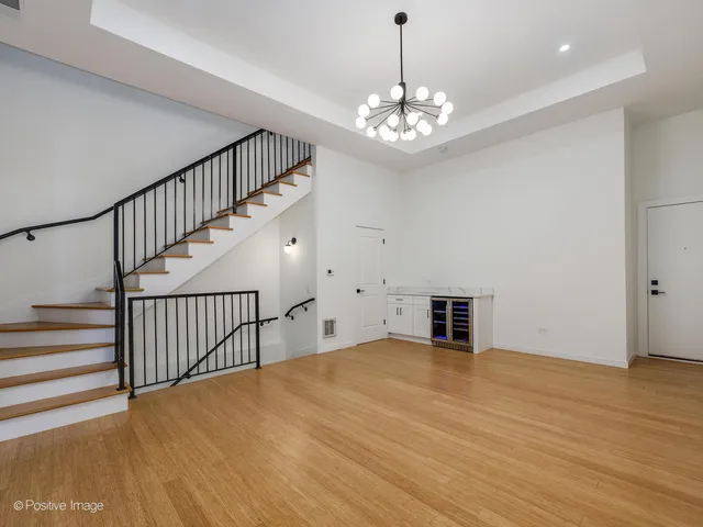 a view of an empty room with wooden floor and chandelier