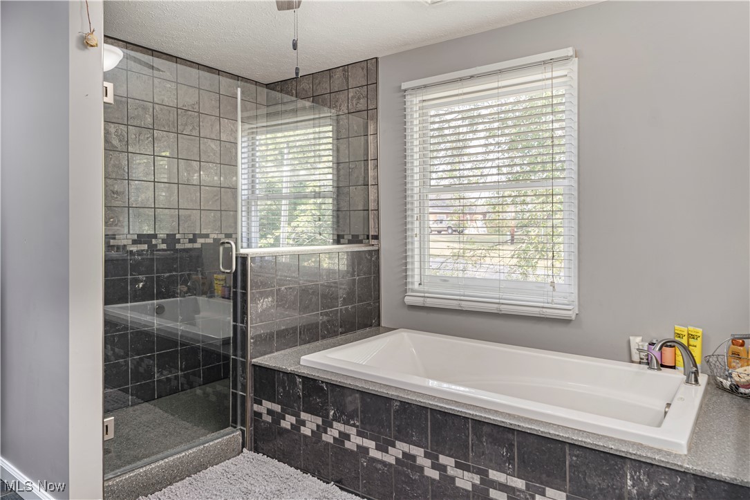 155 Ridgewood Boulevard Belpre, OH 45714 - Photo 39 of 49 Bathroom featuring a shower stall, a bath, and a textured ceiling