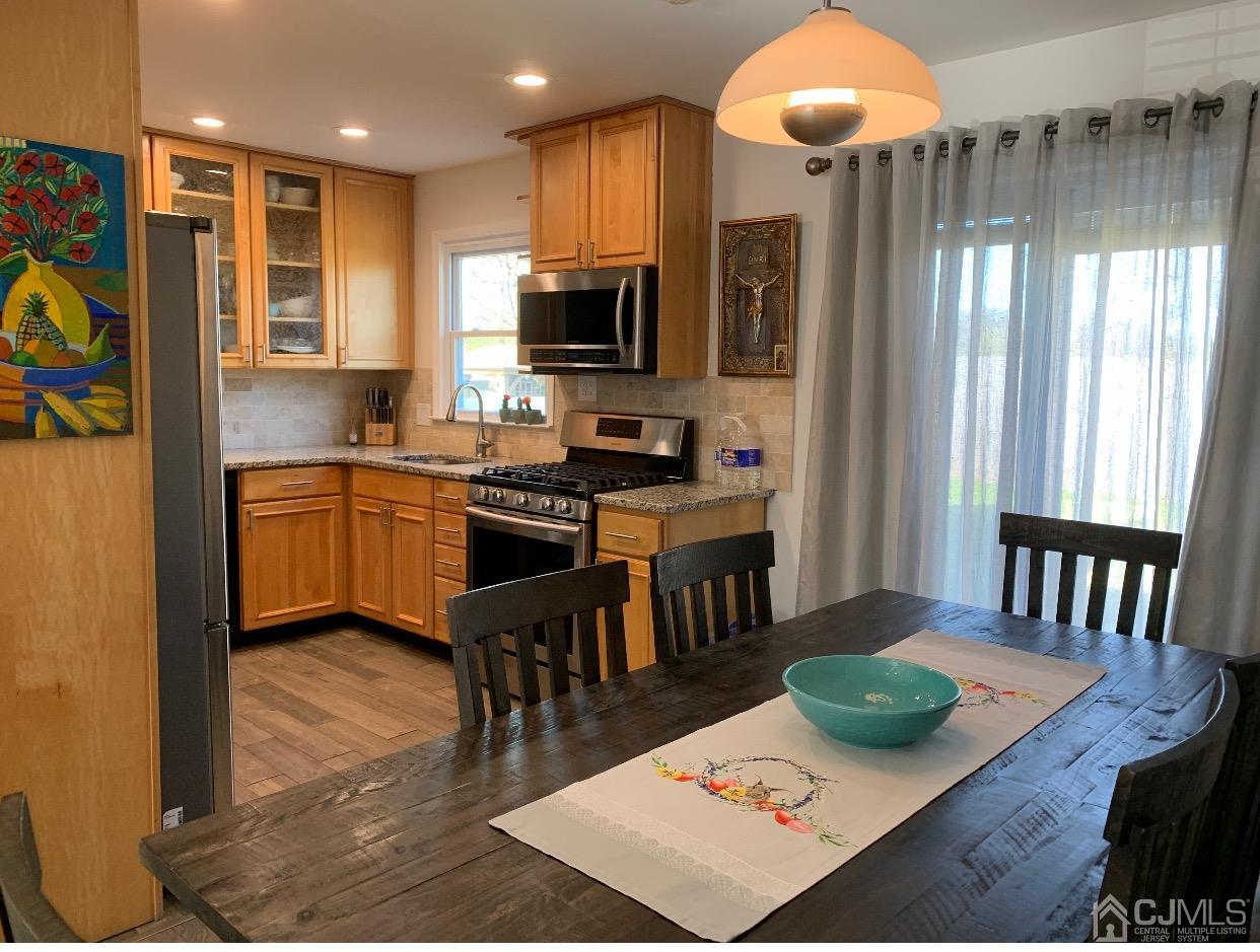 7 Wilshire Road Edison, NJ 08817 - Photo 4 of 14 a kitchen with stainless steel appliances granite countertop a stove top oven a sink a dining table and chairs with wooden floor