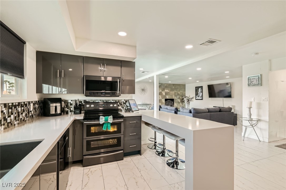 2520 Castlesands Way Las Vegas, NV 89121 - Photo 13 of 59 Kitchen featuring stainless steel appliances, light countertops, tasteful backsplash, modern cabinets, and gray cabinets