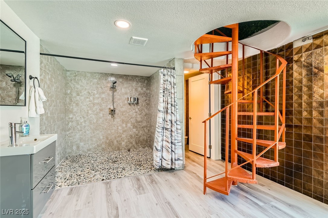 2520 Castlesands Way Las Vegas, NV 89121 - Photo 31 of 59 Bathroom with tiled shower, wood finished floors, vanity, and a textured ceiling