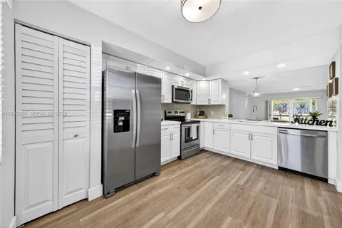 a large kitchen with cabinets wooden floor and stainless steel appliances