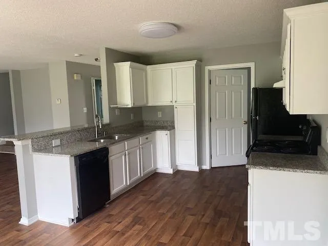 a kitchen with granite countertop a refrigerator and a stove top oven