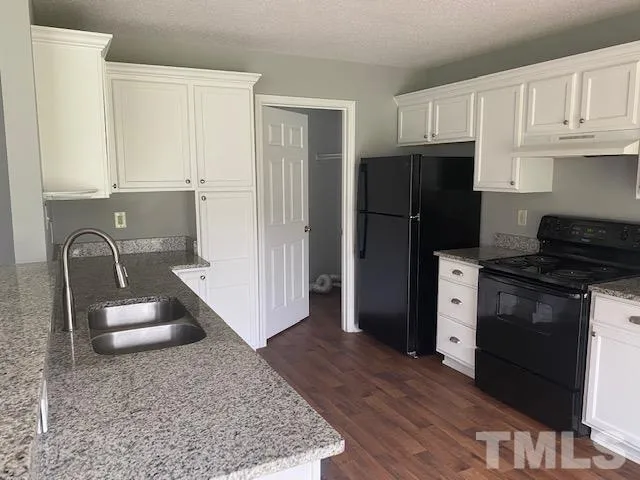 a kitchen with granite countertop a refrigerator stove and sink