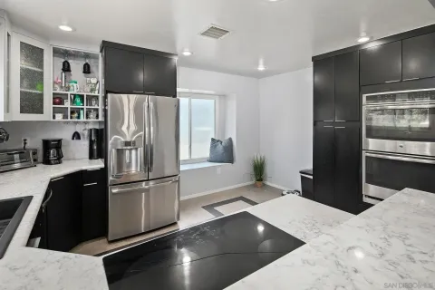 a kitchen with stainless steel appliances kitchen island granite countertop a refrigerator and a sink
