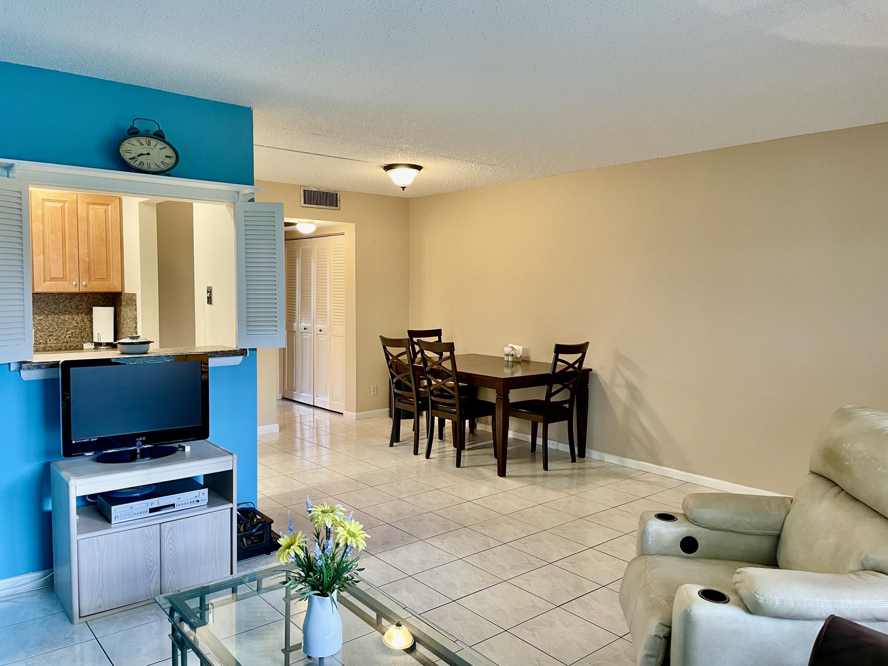 296 Preston H Boca Raton, FL 33434 - Photo 8 of 21 a living room with furniture a large window and a flat screen tv