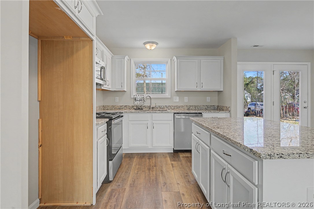 214 Lee Street Spring Lake, NC 28390 - Photo 23 of 44 a kitchen with granite countertop white cabinets and white appliances