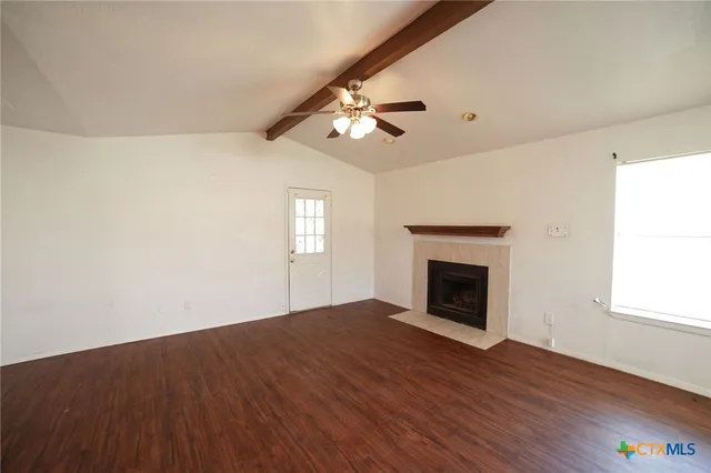 a view of empty room with wooden floor fireplace and window