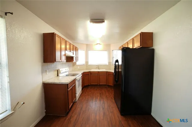 a kitchen with granite countertop a refrigerator stove and sink