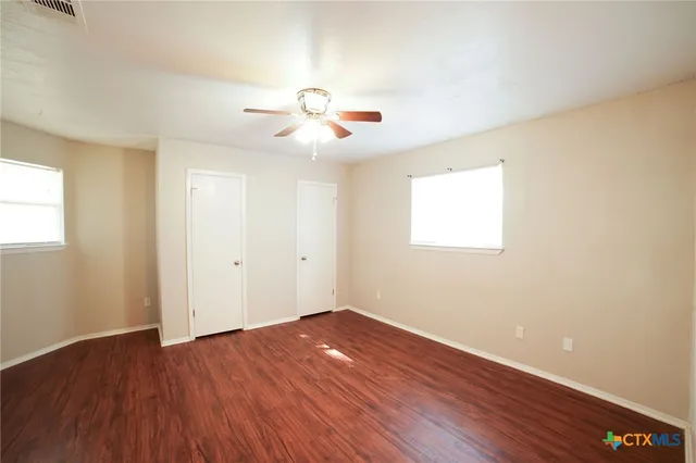 a view of room with hardwood ceiling fan and window