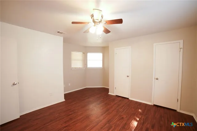 an empty room with wooden floor chandelier fan and closet area