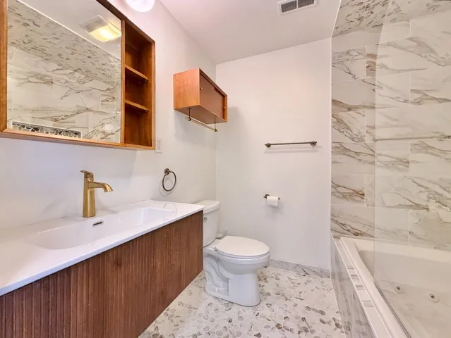 a bathroom with a sink a toilet and shower