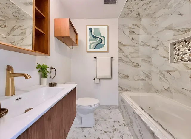 a bathroom with a granite countertop sink a toilet and bathtub