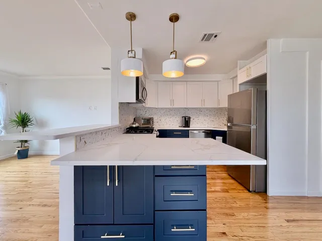a kitchen with a refrigerator a sink and wooden floor