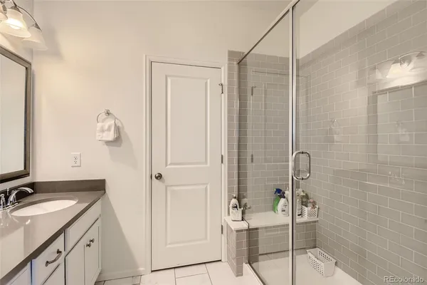 a bathroom with a granite countertop sink a mirror and shower