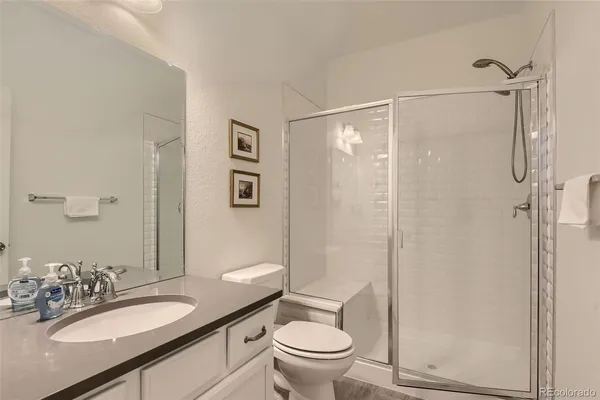 a bathroom with a granite countertop sink toilet a mirror a shower and a mirror