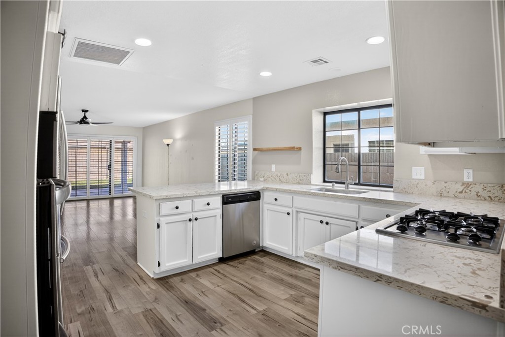 43631 37th Street West Lancaster, CA 93536 - Photo 9 of 38 a kitchen with stainless steel appliances granite countertop a stove a sink dishwasher a refrigerator and white cabinets with wooden floor