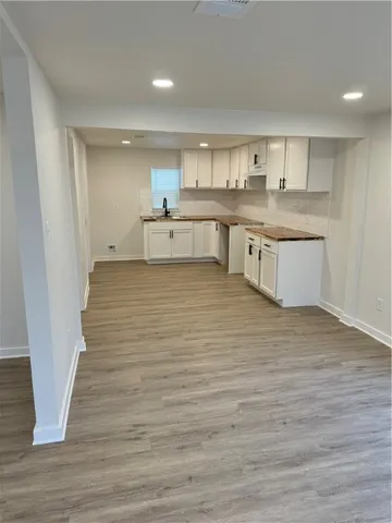 a large white kitchen with kitchen island a sink wooden floor and a refrigerator