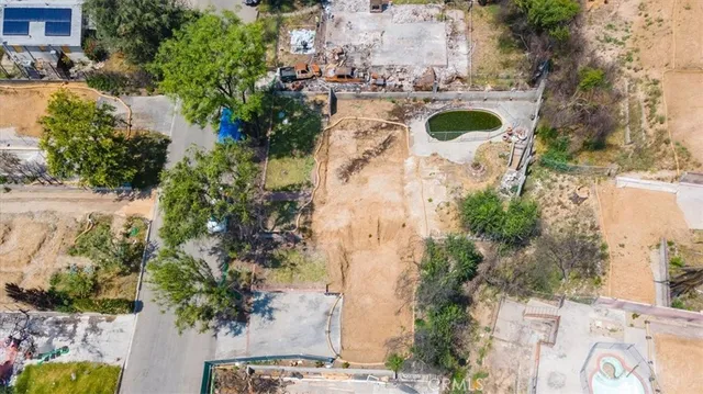 an aerial view of a swimming pool with a yard and lake view in back