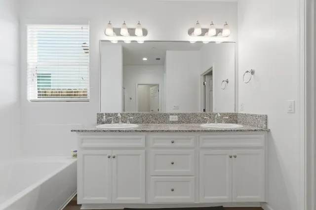 a bathroom with a granite countertop tub sink and mirror