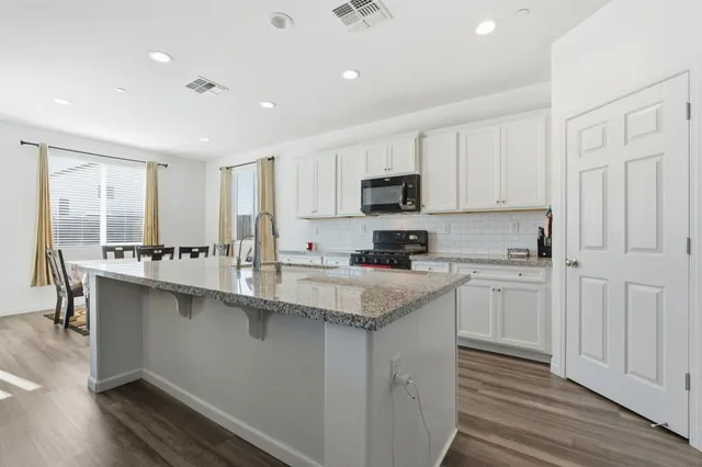 a kitchen with stainless steel appliances granite countertop a stove a sink and a white wooden cabinets