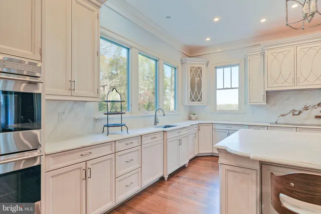a kitchen with white cabinets and wooden floors