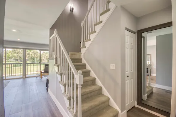 a view of an entryway with wooden floor leading to a furnished livingroom and windows