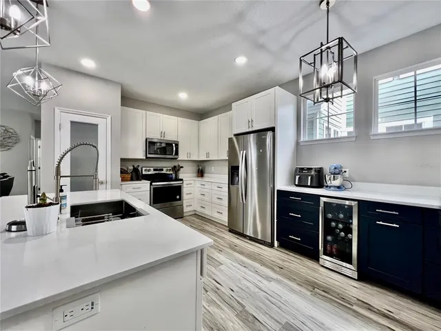 a large kitchen with cabinets wooden floor stainless steel appliances and a window