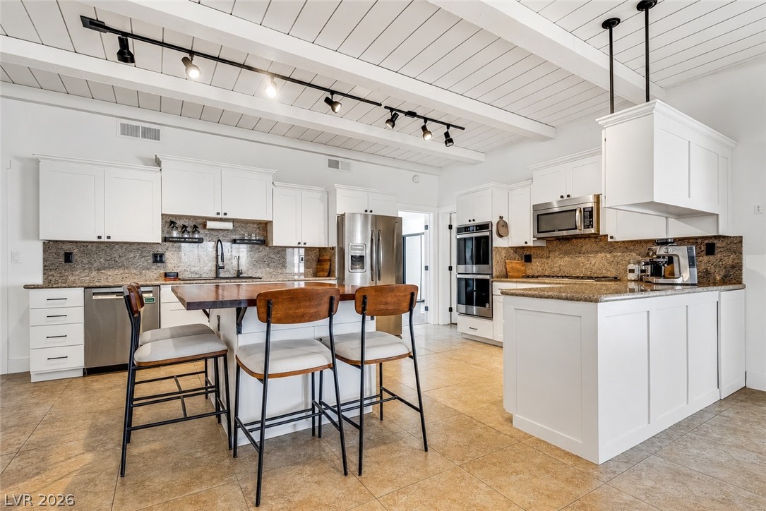 524 Swallow Cove Boulder City, NV 89005 - Photo 12 of 58 White exposed beams complement the warm tile flooring and granite countertops in this modern kitchen.
