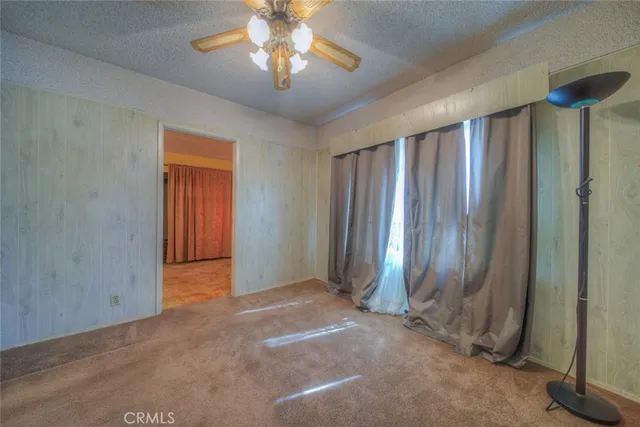 an empty room with chandelier fan and closet