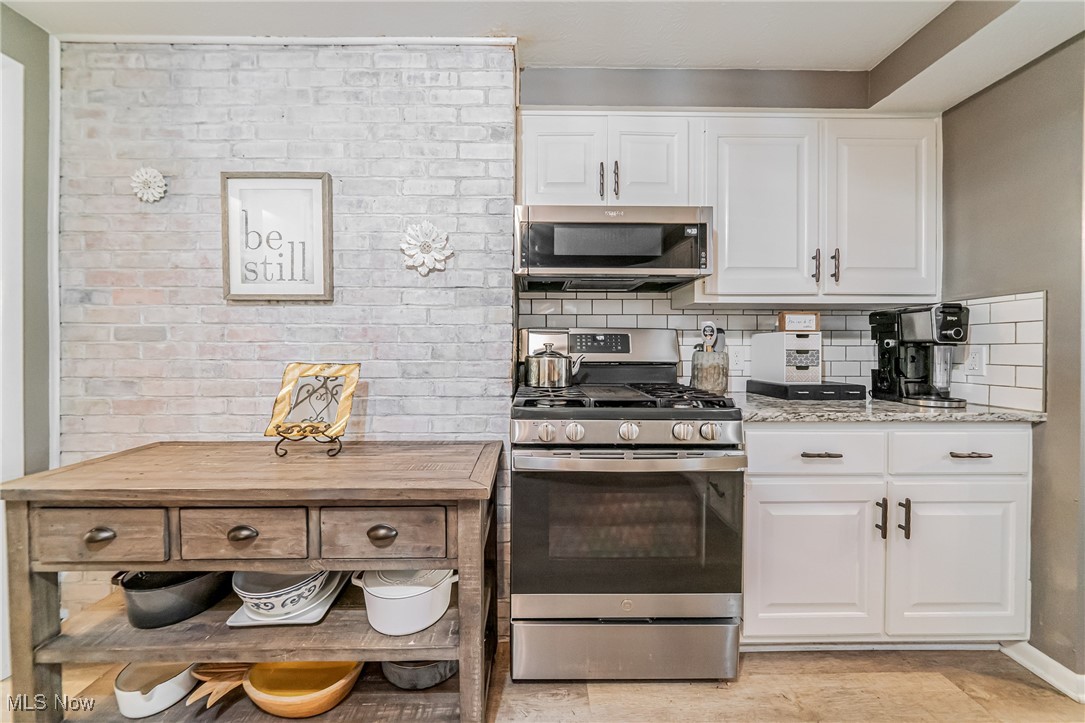 595 Moorfield Road Fairlawn, OH 44313 - Photo 11 of 50 Kitchen featuring appliances with stainless steel finishes, white cabinets, decorative backsplash, and light stone counters