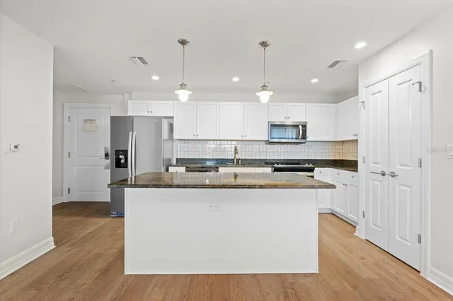 a kitchen with kitchen island stainless steel appliances a stove a sink and a wooden floor