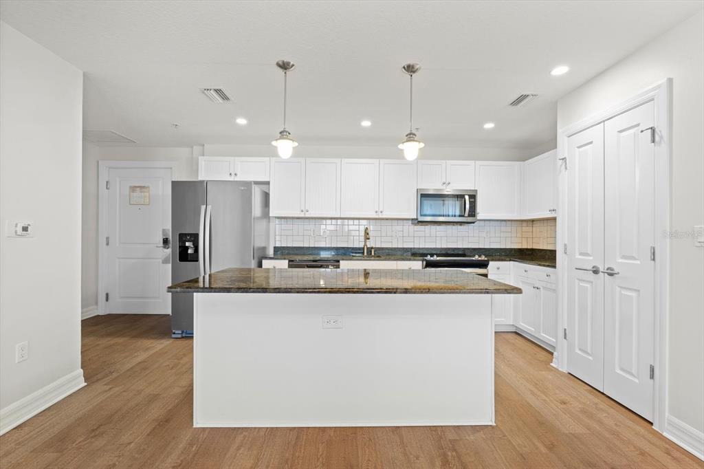 536 Bahia Beach Boulevard, Unit 102A Ruskin, FL 33570 - Photo 4 of 28 a kitchen with kitchen island stainless steel appliances a stove a sink and a wooden floor