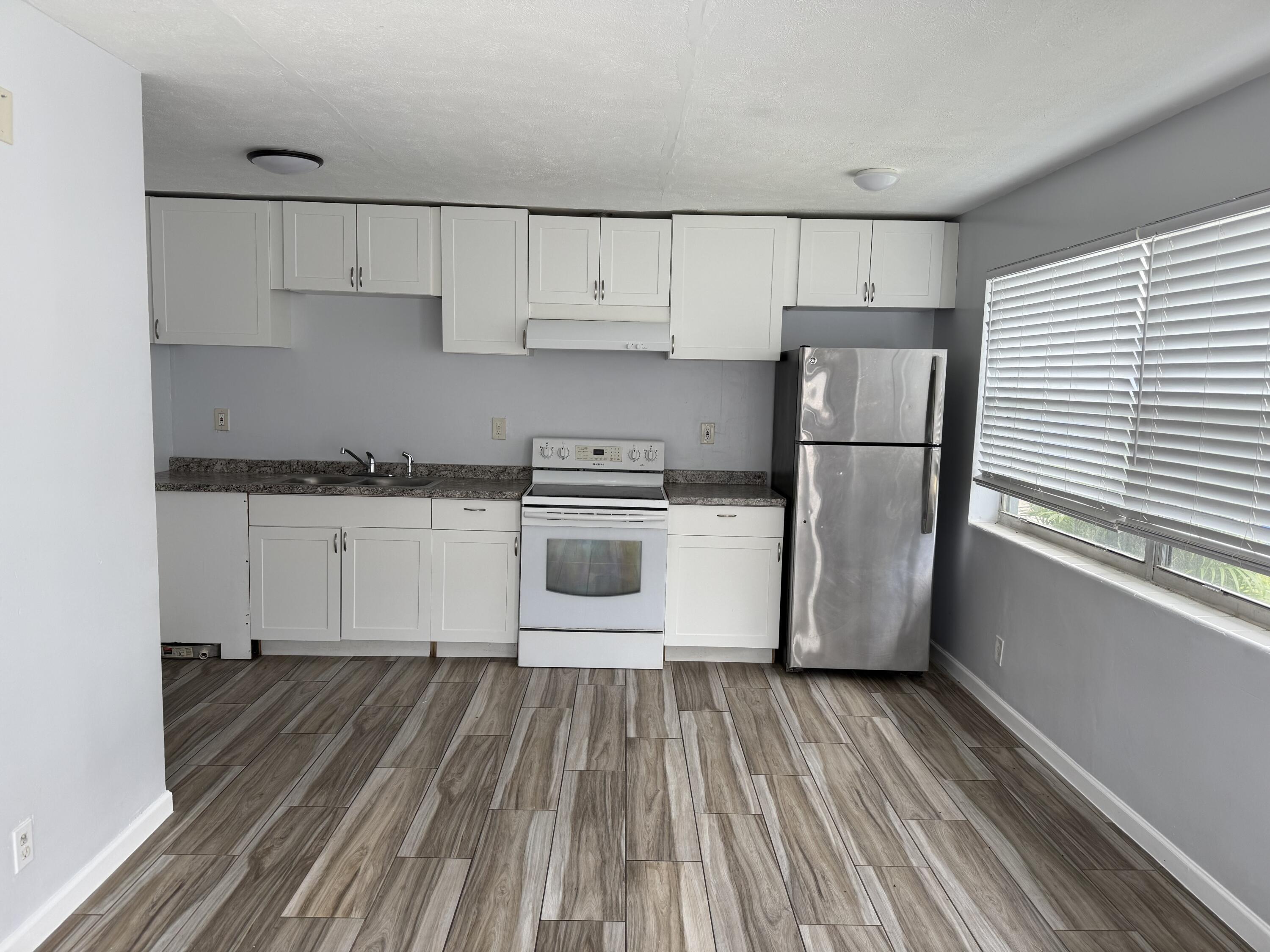 111 East 27th Street, Unit 113B Riviera Beach, FL 33404 - Photo 2 of 5 a kitchen with cabinets a refrigerator and wooden floor