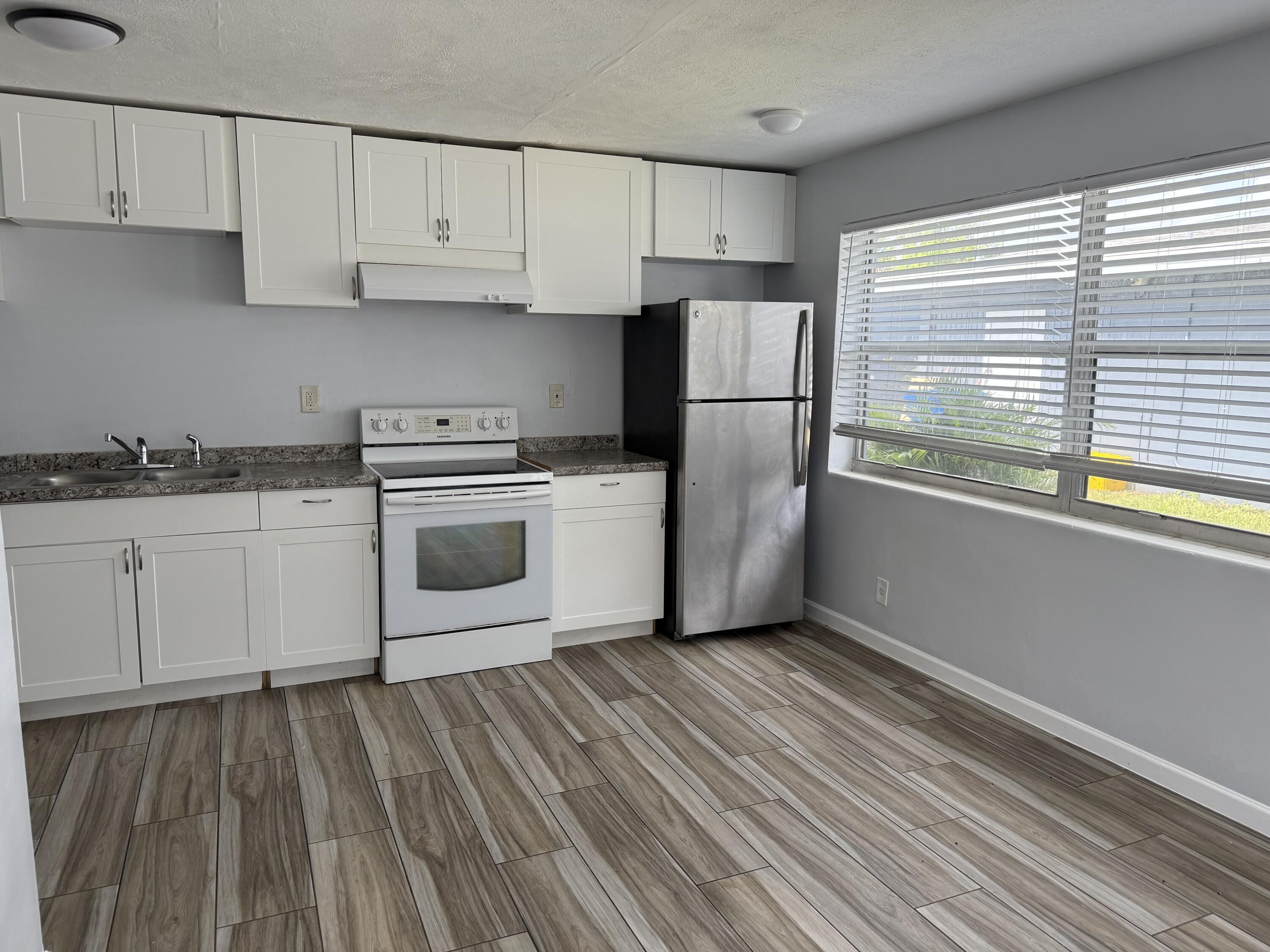 111 East 27th Street, Unit 113B Riviera Beach, FL 33404 - Photo 3 of 5 a kitchen with a white cabinets and wooden floor