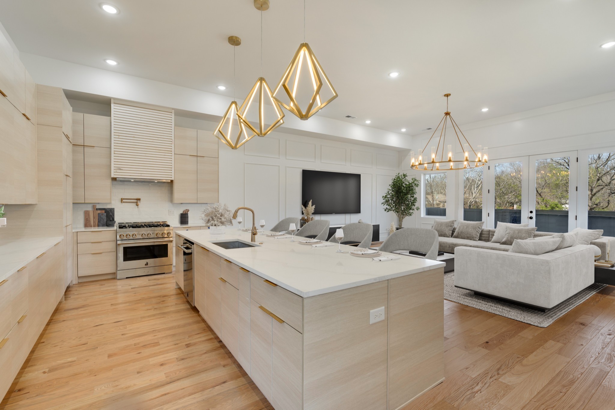 a large white kitchen with a large island oven a stove and a chandelier