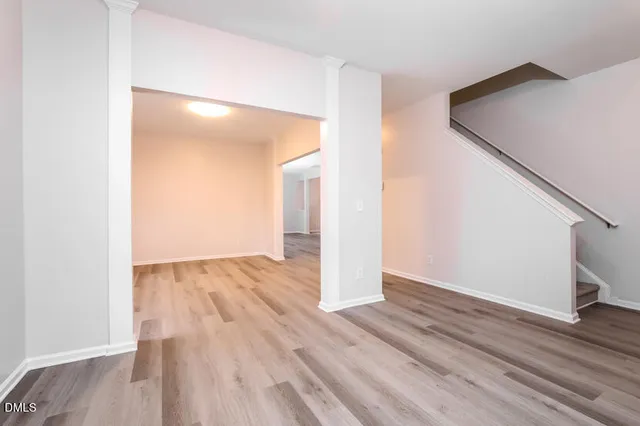 a view of an empty room with wooden floor and a hallway