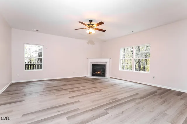 a view of an empty room with window and chandelier fan