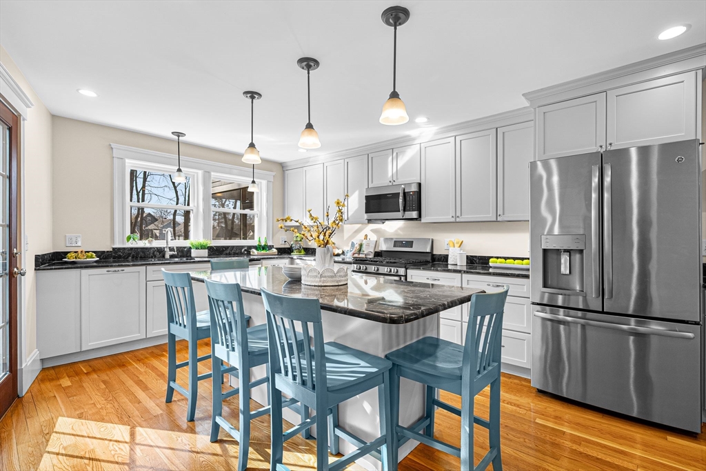 57 Edmund Road Arlington, MA 02474 - Photo 4 of 36 a kitchen with stainless steel appliances granite countertop a table chairs refrigerator and microwave