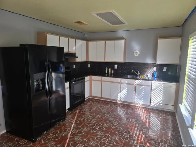 a kitchen with granite countertop a refrigerator and a sink