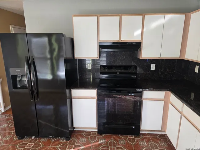 a kitchen with stainless steel appliances granite countertop a refrigerator a stove and a sink