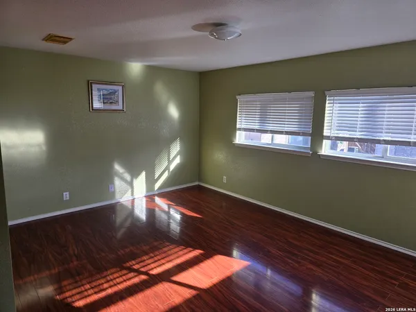 a view of an empty room with window and wooden floor
