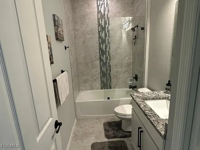 a bathroom with a granite countertop bathtub shower and toilet