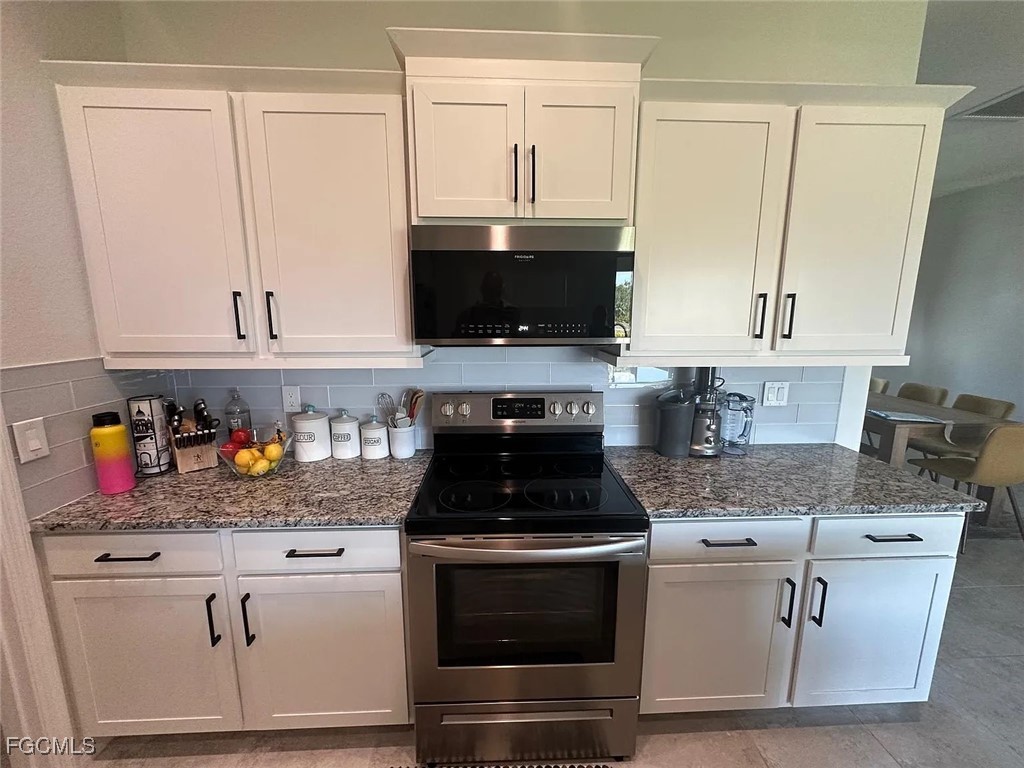 4117 Northwest 22nd Street Cape Coral, FL 33993 - Photo 25 of 31 a kitchen with white cabinets and black appliances