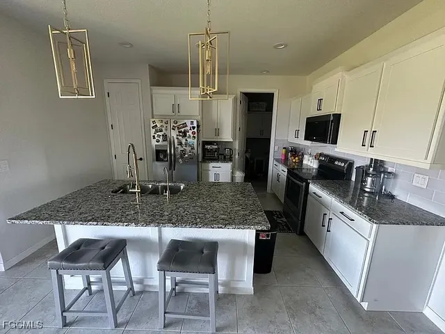 a kitchen with stainless steel appliances granite countertop a sink and a refrigerator