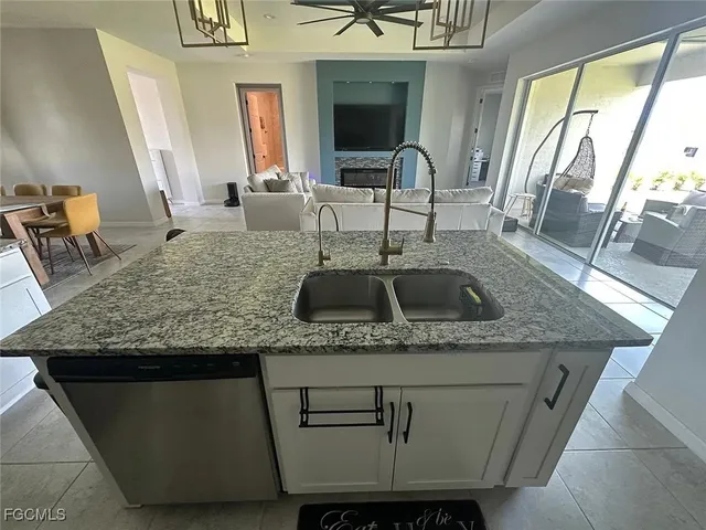 a kitchen with a sink a counter top space and living room view