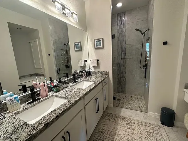 a bathroom with a granite countertop sink a mirror and a shower