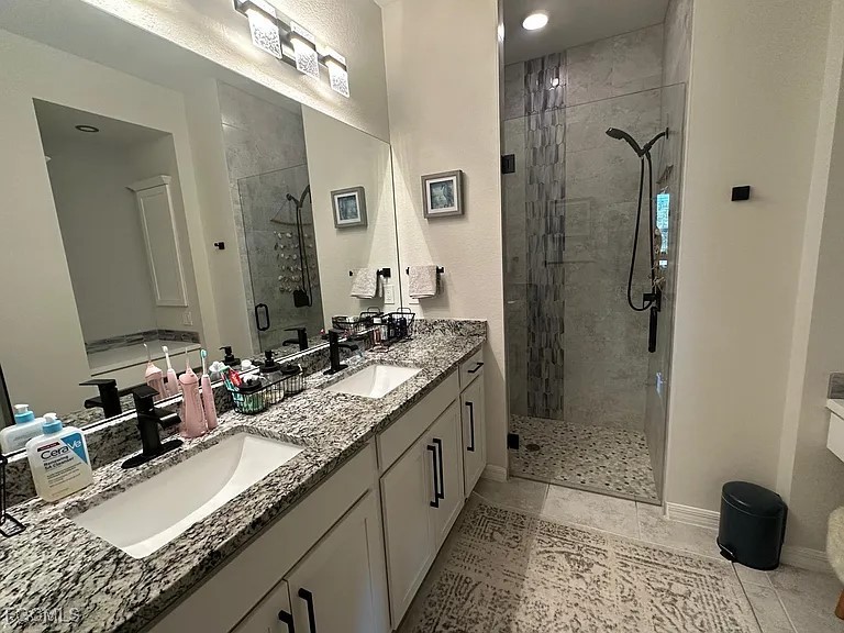4117 Northwest 22nd Street Cape Coral, FL 33993 - Photo 10 of 31 a bathroom with a granite countertop sink a mirror and a shower
