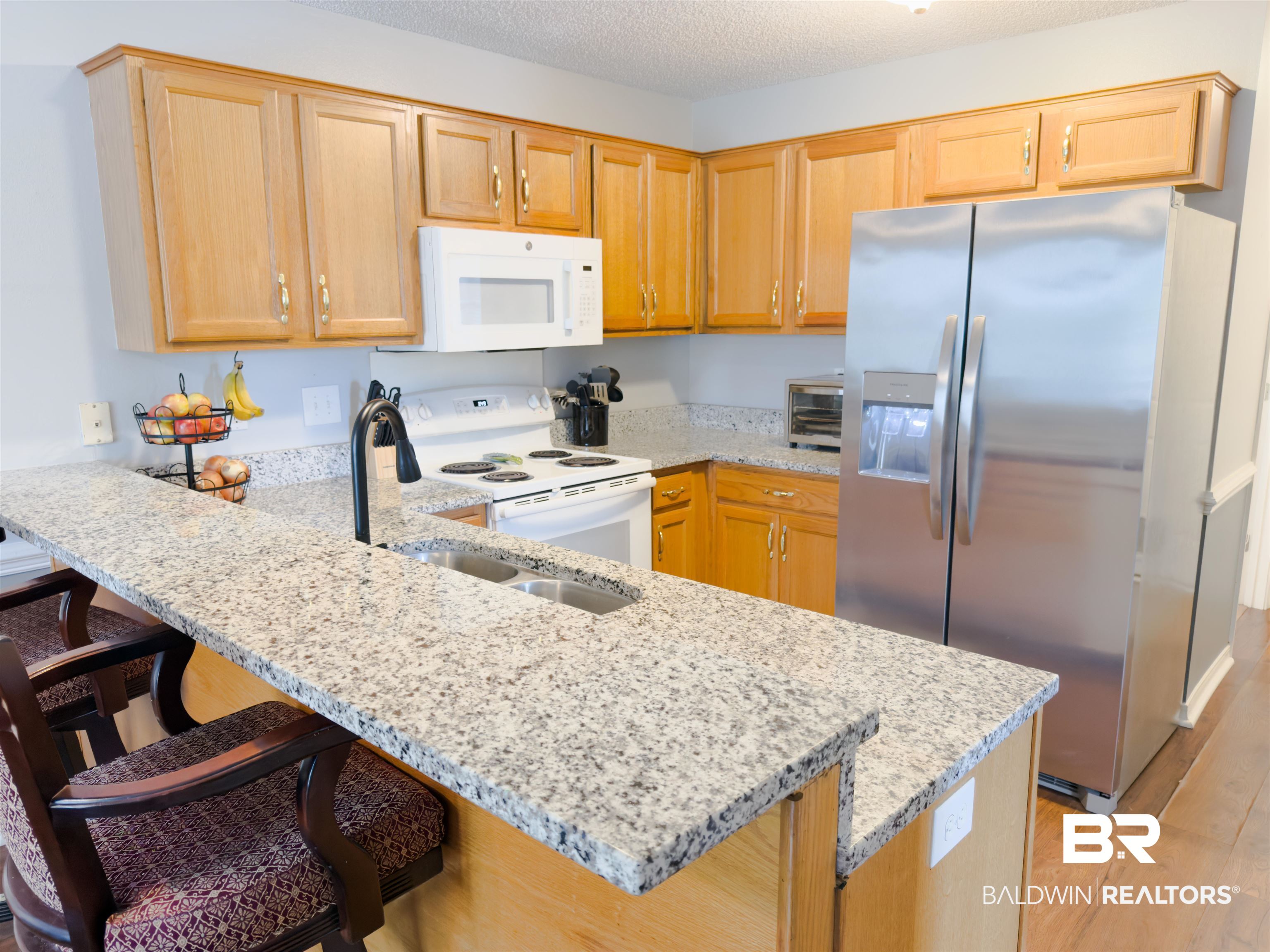 129 Pennbrooke Loop Foley, AL 36535 - Photo 21 of 44 Kitchen featuring white appliances, a peninsula, light stone counters, a breakfast bar area, and a textured ceiling